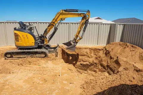 Mini excavator digging in a fenced back yard