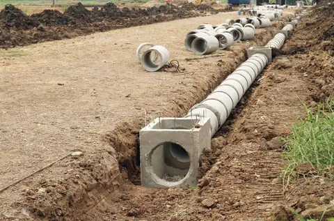 Concrete drainage pipe and inlet box set in a trench